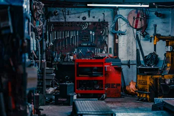 Kfz-Werkstatt mit einer Hebebühne, Schraubenschlüsseln, Werkzeugwagen und Reifenmontiermaschine.