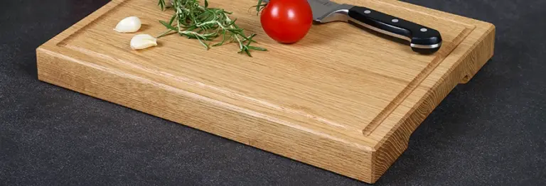 Schneidebrett aus Eichenholz mit einer Saftrille und dekoriert mit Küchenutensilien