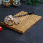 Brotschneidebrett aus Eiche mit Krümelmulden, Brotlaib und Messer auf der Arbeitsfläche
