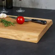 Detailaufnahme der natürlichen Holzmaserung und der elegant gefasten Kante eines rustikalen Schneidebrettes aus Eiche