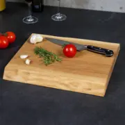 Handgefertigtes Schneidebrett aus geölter Eiche, dekoriert mit Küchenutensilien, mit natürlichen Baumkanten