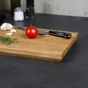 Handgefertigtes, geöltes Schneidebrett aus Massivholz, dekoriert mit Küchenutensilien